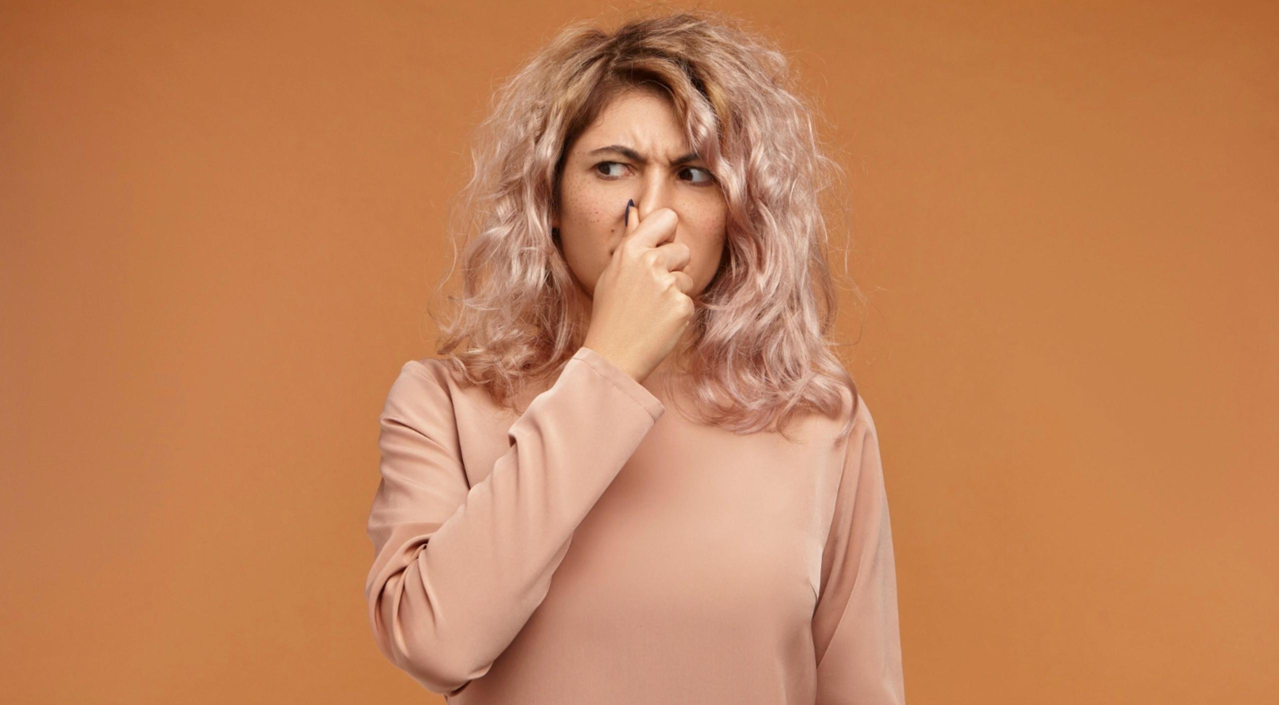 woman pinching nose smelling bad smell
